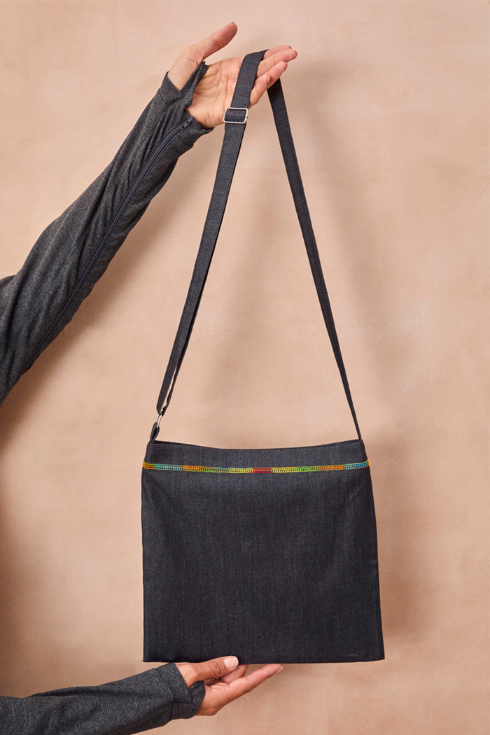 Charcoal Life is Tough Honey Drainage Bag with rainbow stitching and an adjustable shoulder strap, held by a model.