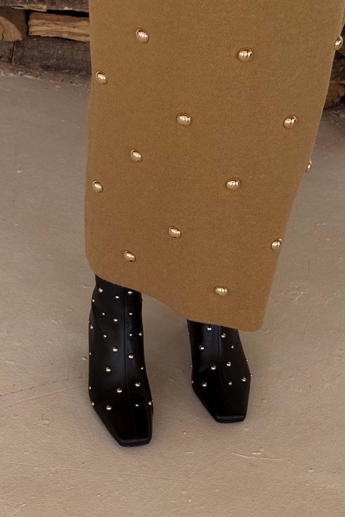 Black Leather Boots featuring gold metal studs and a square toe, styled with a tan studded skirt.