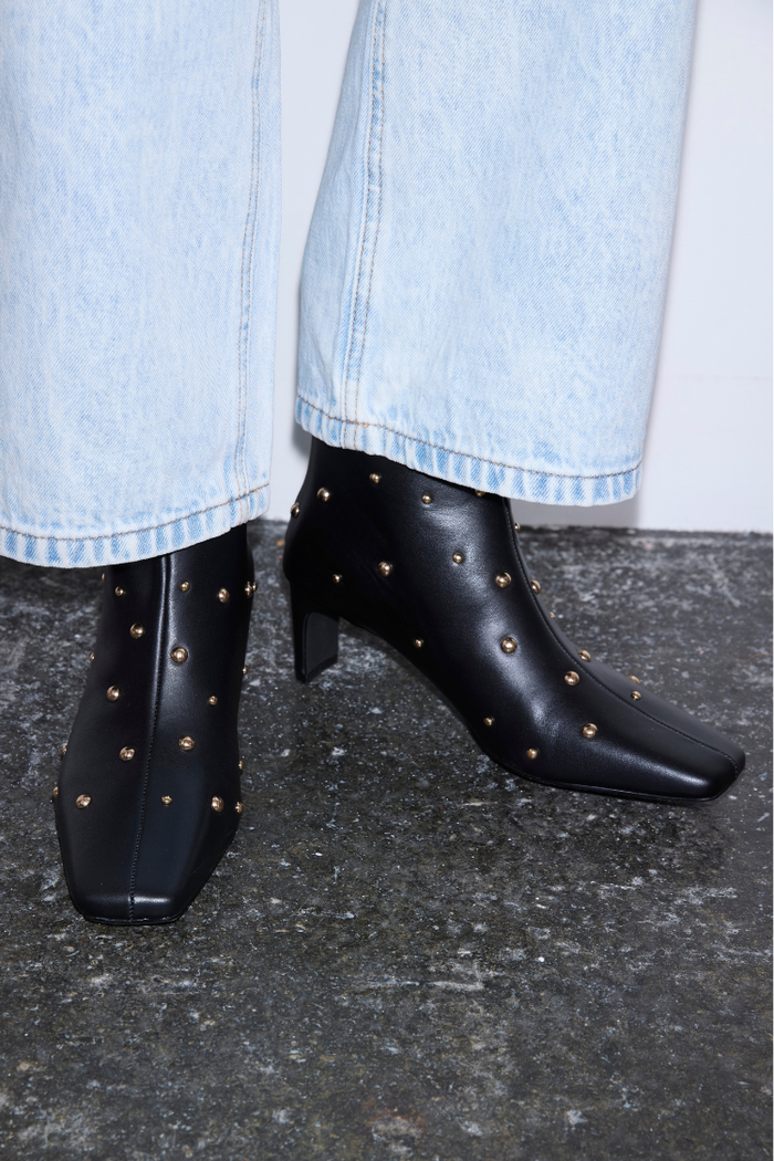 Black Leather Boots with Gold Studs, square toe and block heel, styled with light-wash denim jeans.