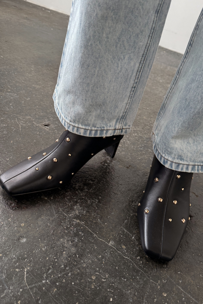 Black leather boots with gold metal studs and a square toe, a wardrobe staple paired with denim.
