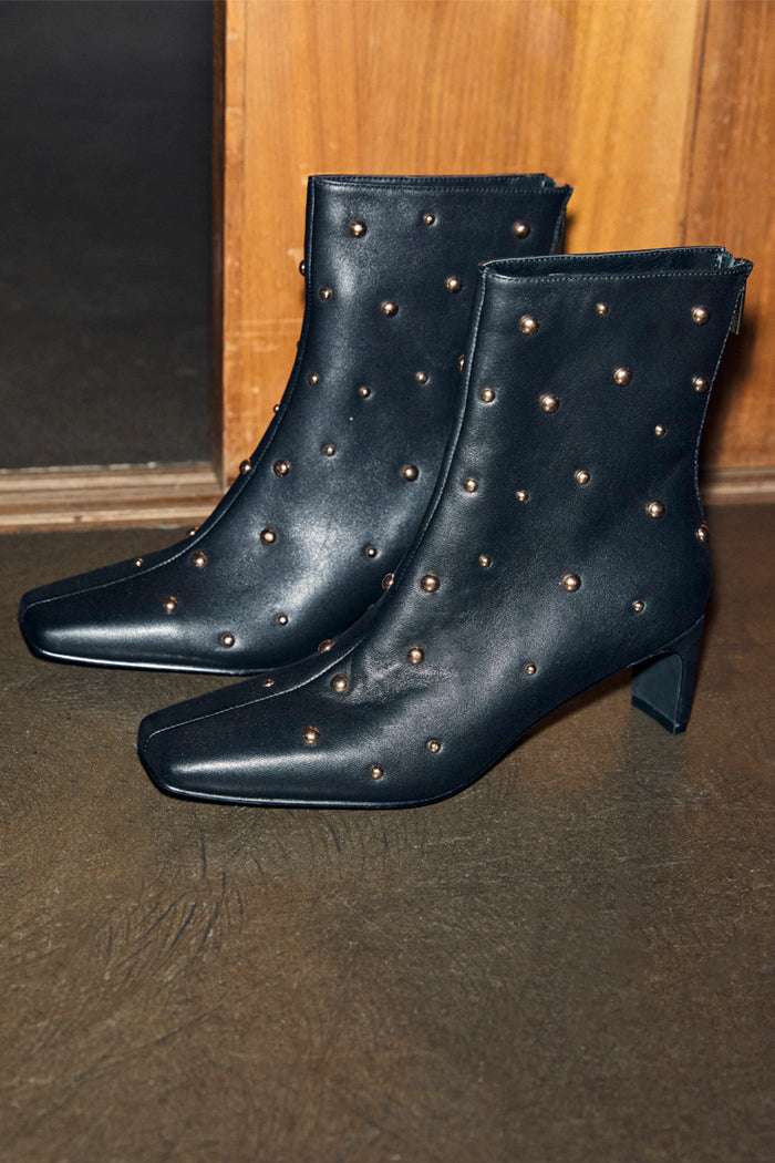 Black leather boots with all-over gold metal studs, a square toe and a thin block heel for a London look.