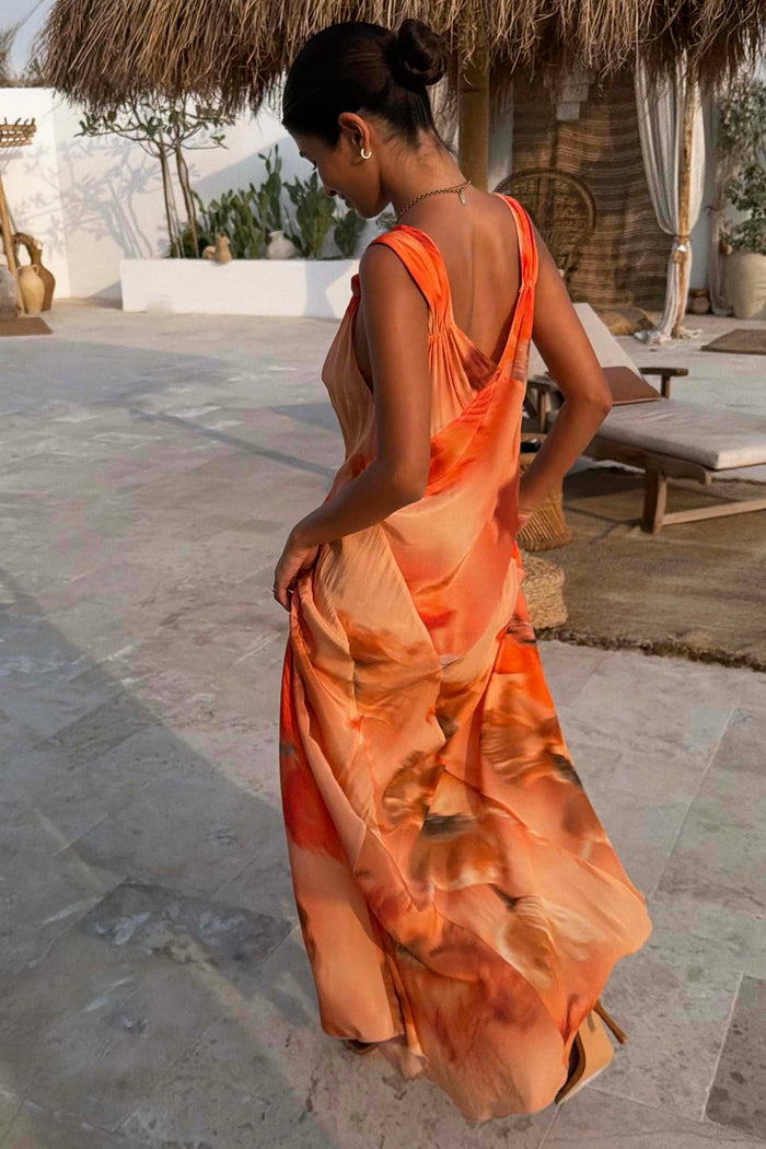 Iconic Blurred Floral Sofia Dress in burnt orange with tie-knot shoulders, styled for a sunny vacation.