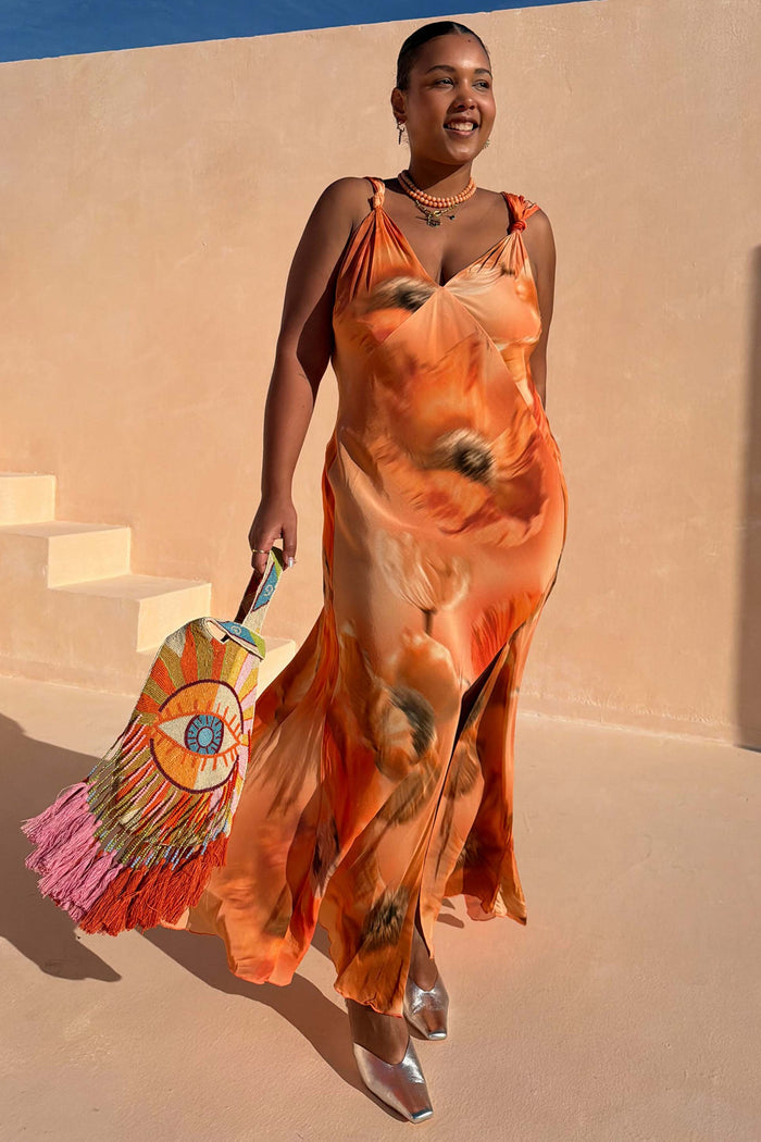 Burnt orange Blurred Floral Sofia Dress with tie-knot shoulders and side slit, styled for a summer wedding guest.