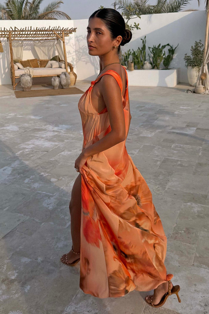 Burnt orange Blurred Floral Sofia Dress with tie-knot shoulders and a side slit, styled for a summer vacation.