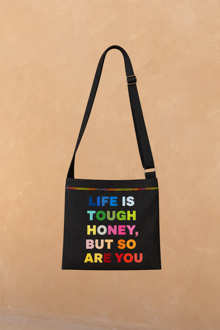 Charcoal Life is Tough Honey Drainage Bag with multicoloured lettering, rainbow stitching and an adjustable crossbody strap.