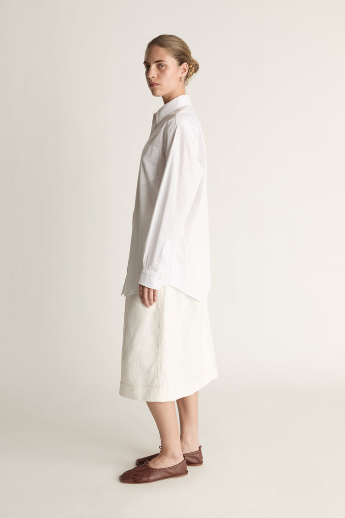 Person wearing a long white shirt and skirt on a plain background