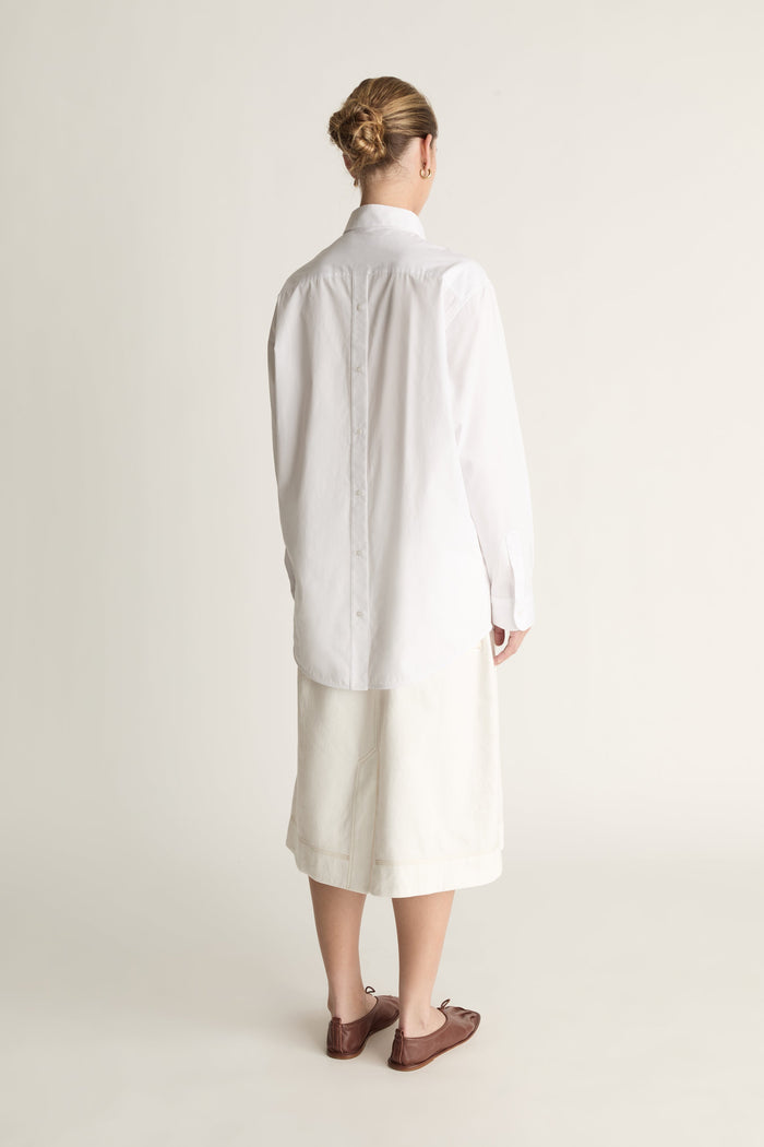 Person wearing a long white shirt and skirt on a plain background