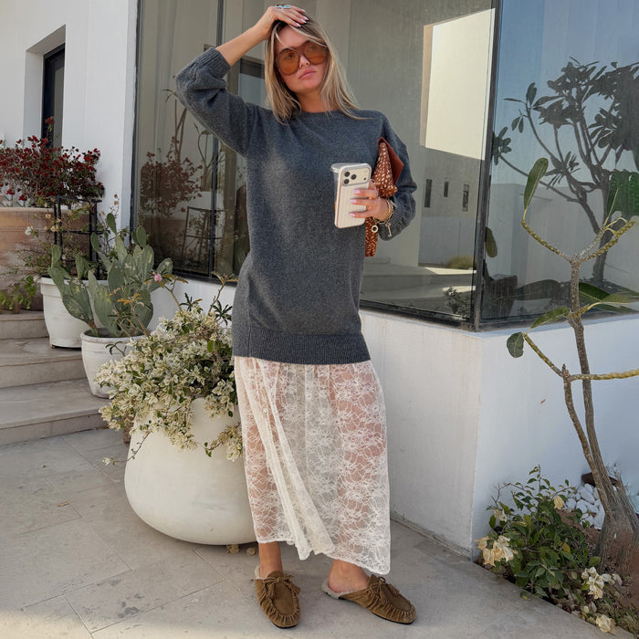 Grey knit jumper dress with a delicate white sheer lace skirt, styled with sunglasses for a casual street style look.