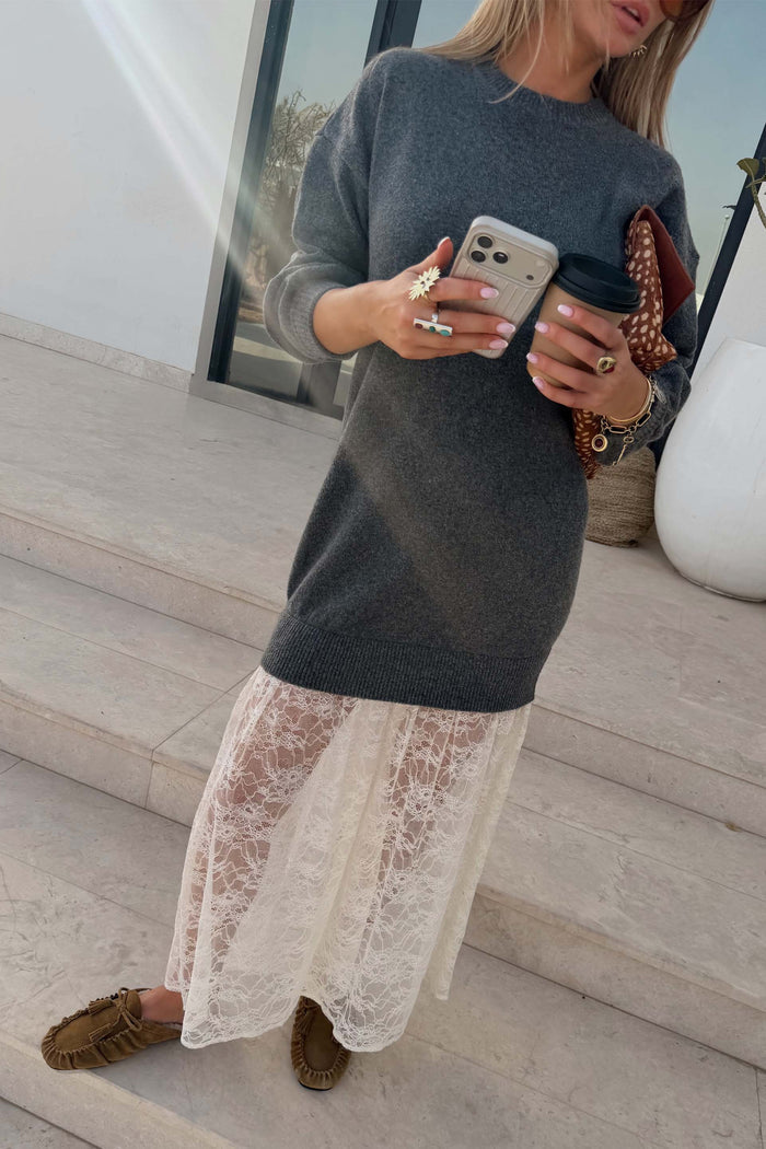 Grey Knit Jumper Dress with a sheer white lace skirt, styled with brown loafers and a coffee on stone steps.