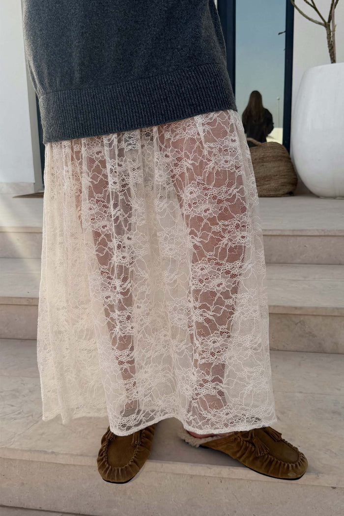 Grey knit jumper dress with a sheer white floral lace skirt, styled with tasseled brown suede loafers.