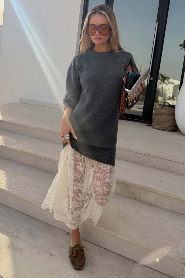 Grey Knit Jumper Dress with a sheer white lace skirt, styled with sunglasses and loafers on stone steps.