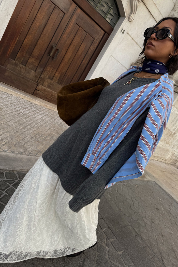 Grey Knit Jumper Dress with a sheer cream lace skirt, layered with a blue striped shirt and brown suede bag.