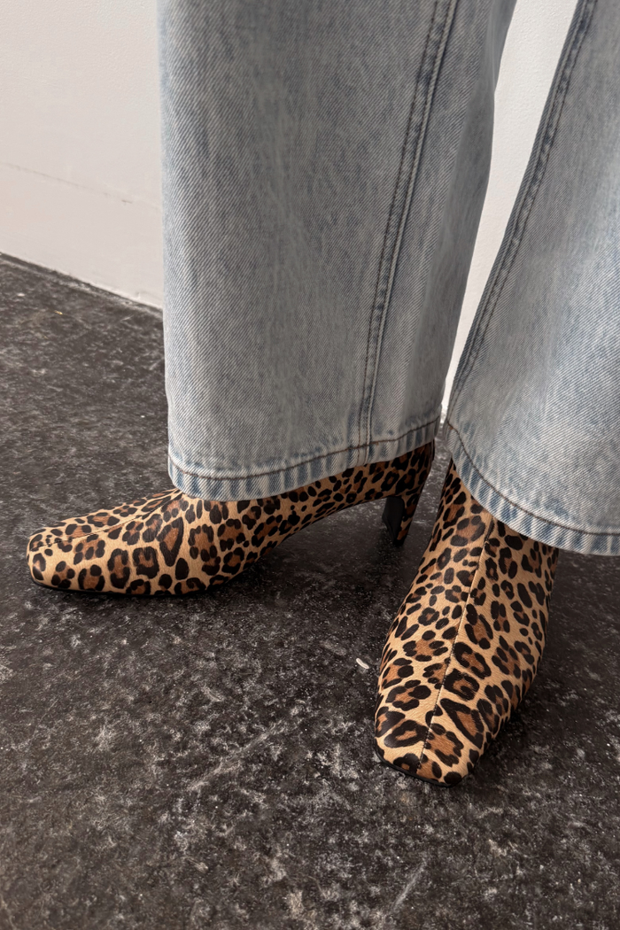 Leopard print boots with a square toe and thin block heel, paired with light blue denim jeans.
