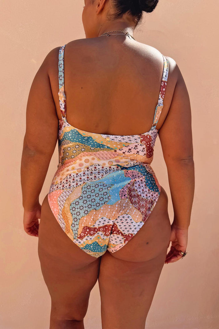 Morocco Swimsuit featuring a swirling patchwork print in pink and blue tones, shown from the back on a curve model.