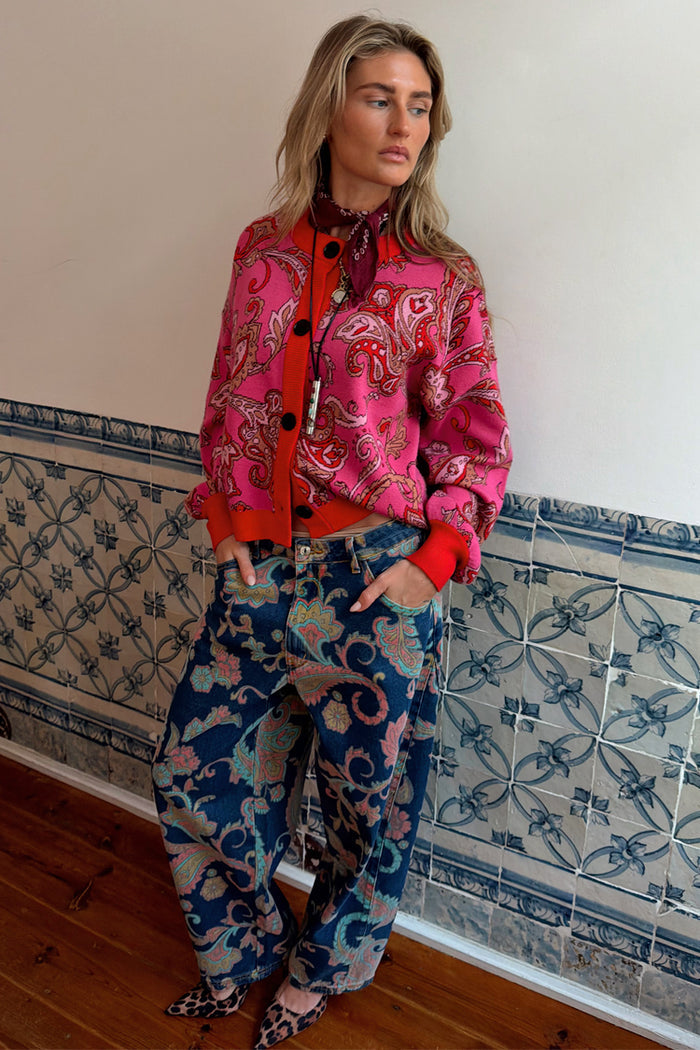 Pink Paisley Oslo Cardigan with red ribbed trims and intricate print, styled with blue paisley jeans and leopard heels.