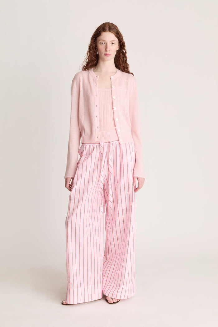 Woman wearing pink knit shirt and cardigan with pink striped pants on a white background