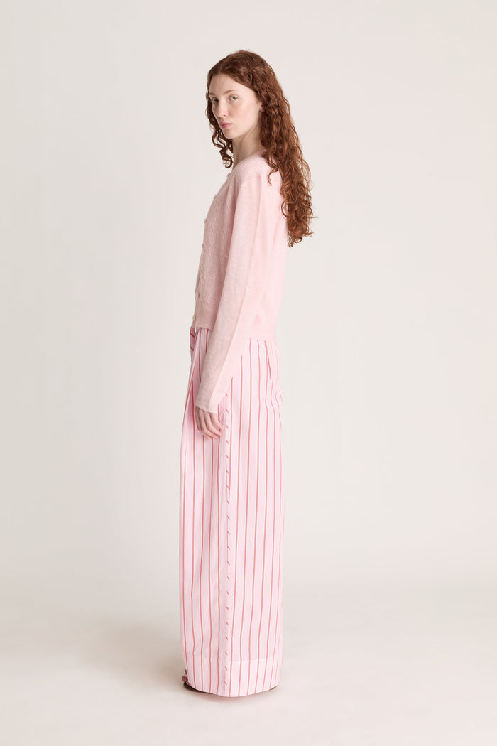 Woman wearing pink knit shirt and cardigan with pink striped pants on a white background