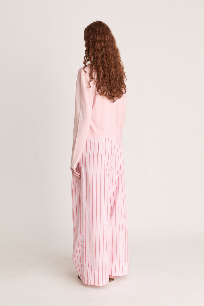 Woman wearing pink knit shirt and cardigan with pink striped pants on a white background