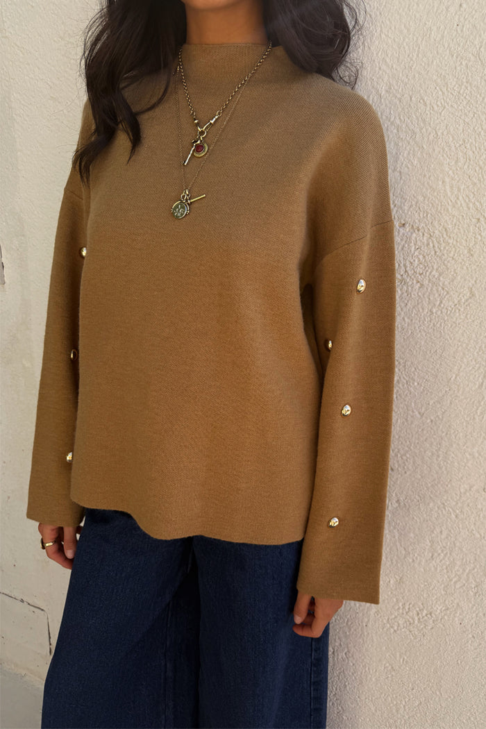 Tan Stud Evie Knit Jumper with gold stud details on long sleeves, paired with dark wash jeans.